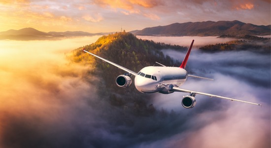 airplane-flying-over-island-during-sunrise