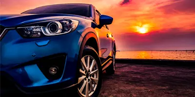 blue-car-on-beach-at-sunset